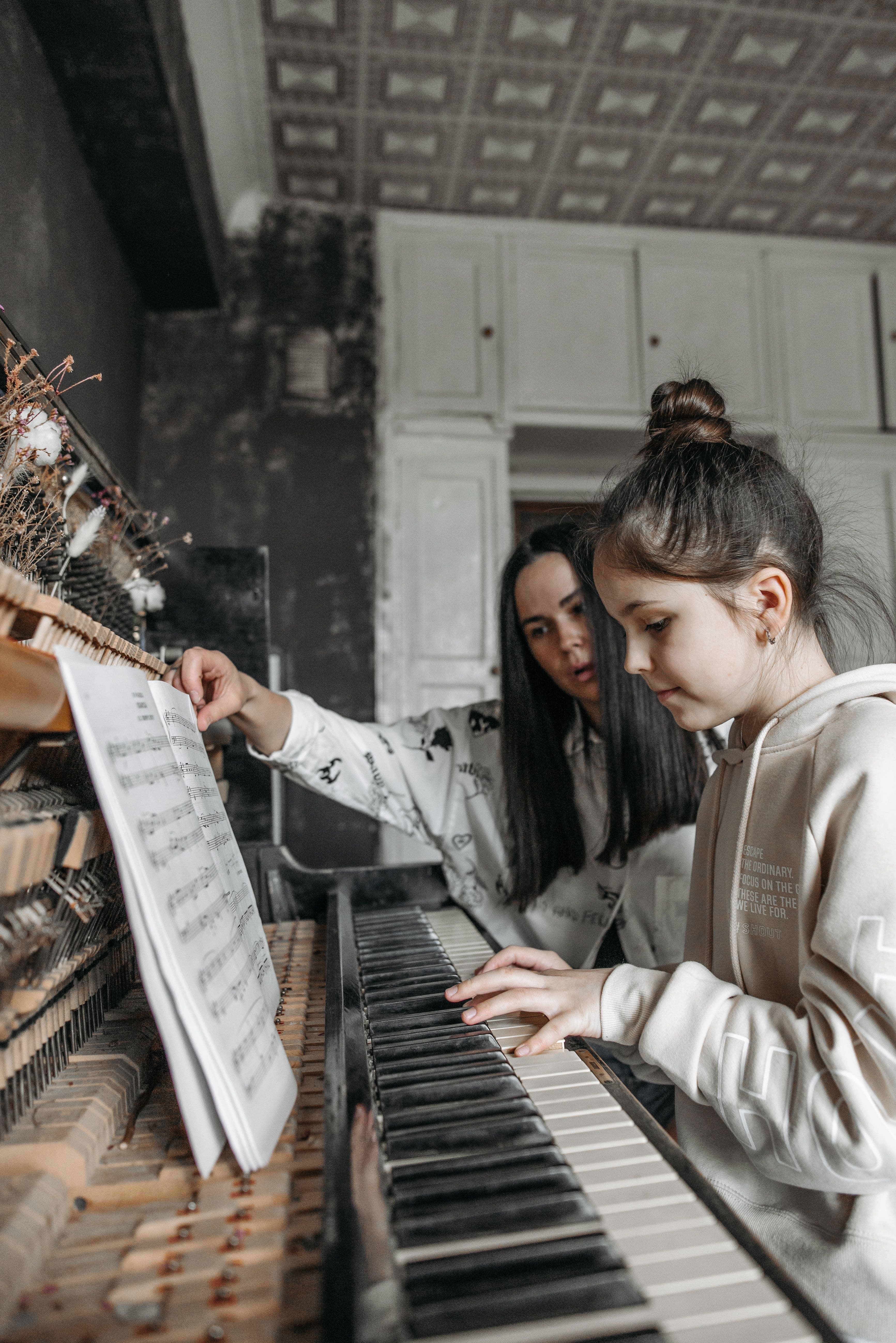 Piano tutor guiding a young student during a lesson