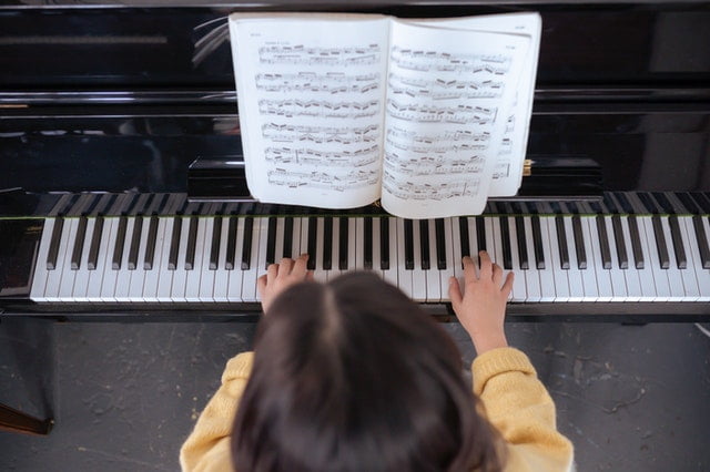 girl playing piano with sheet music
