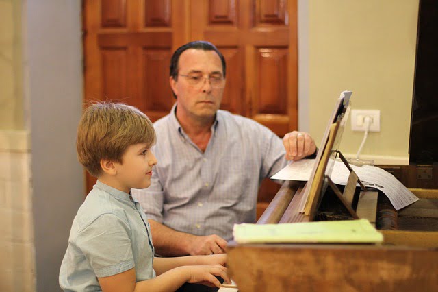 boy playing piano with tutor